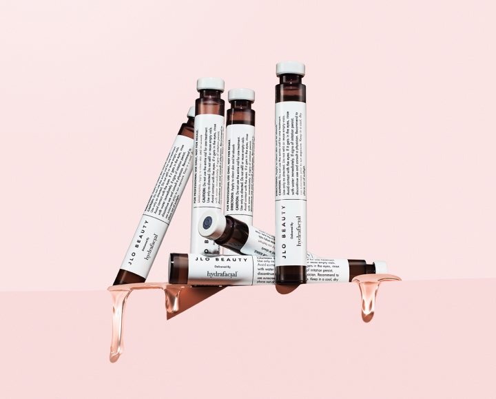 JLo Beauty booster vials for HydraFacial treatment on a pink background